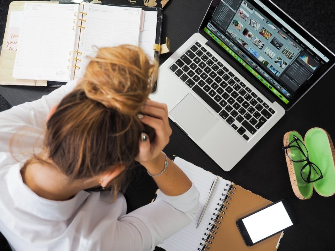 women putting on hair curler in front of a macbook